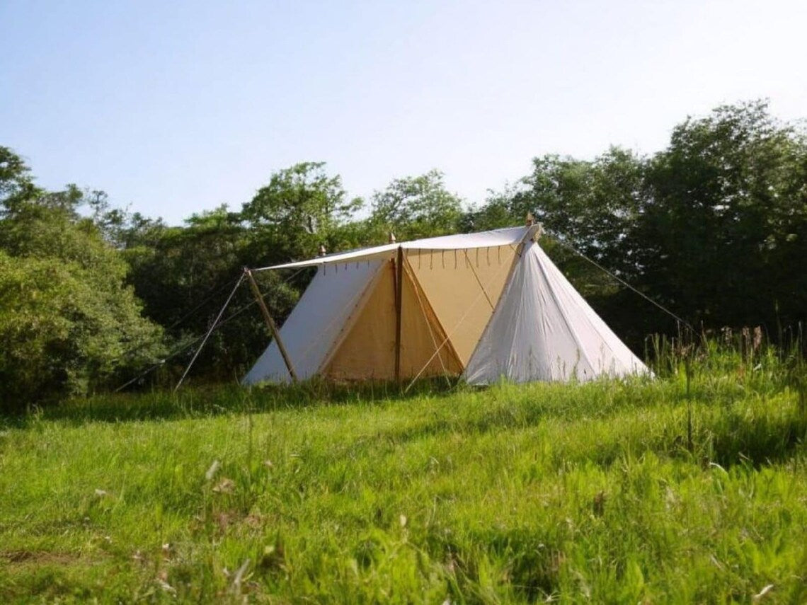 Tent set up in a grassy area with trees in the background