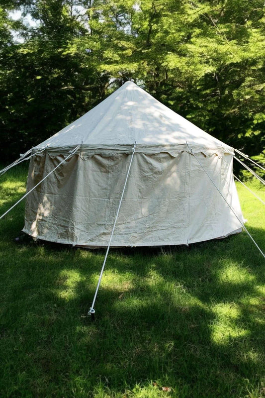 White tent set up on grass with trees in the background