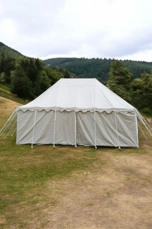 Large white tent set up outdoors with a scenic background of trees and hills.