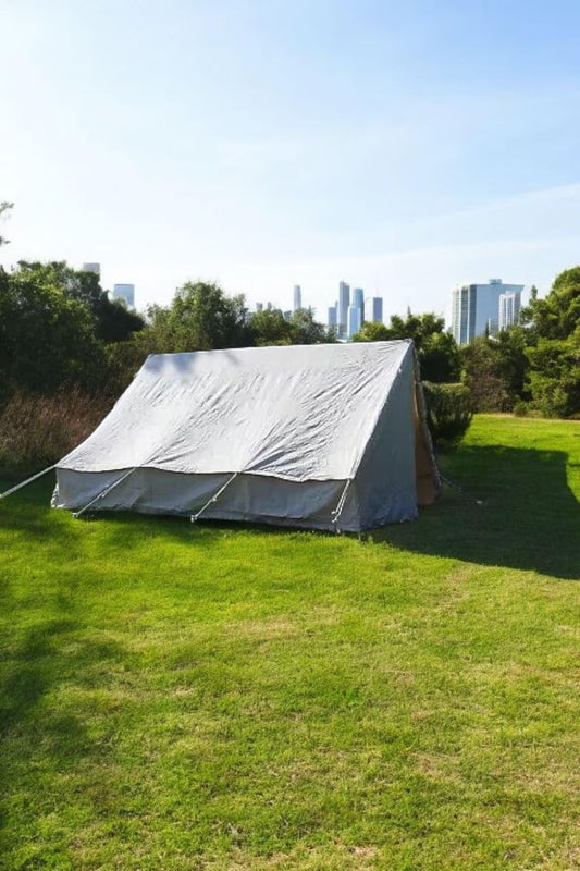White tent on grass with city skyline in the background