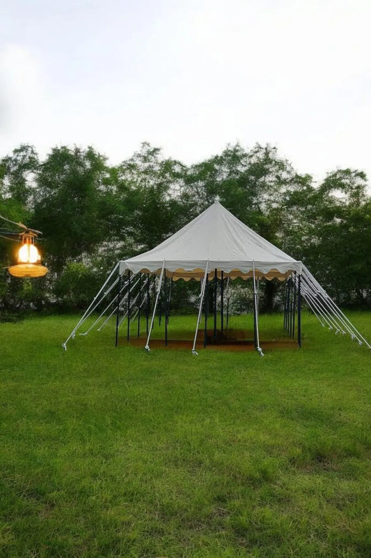 White tent with decorative elements on a grassy field with trees in the background