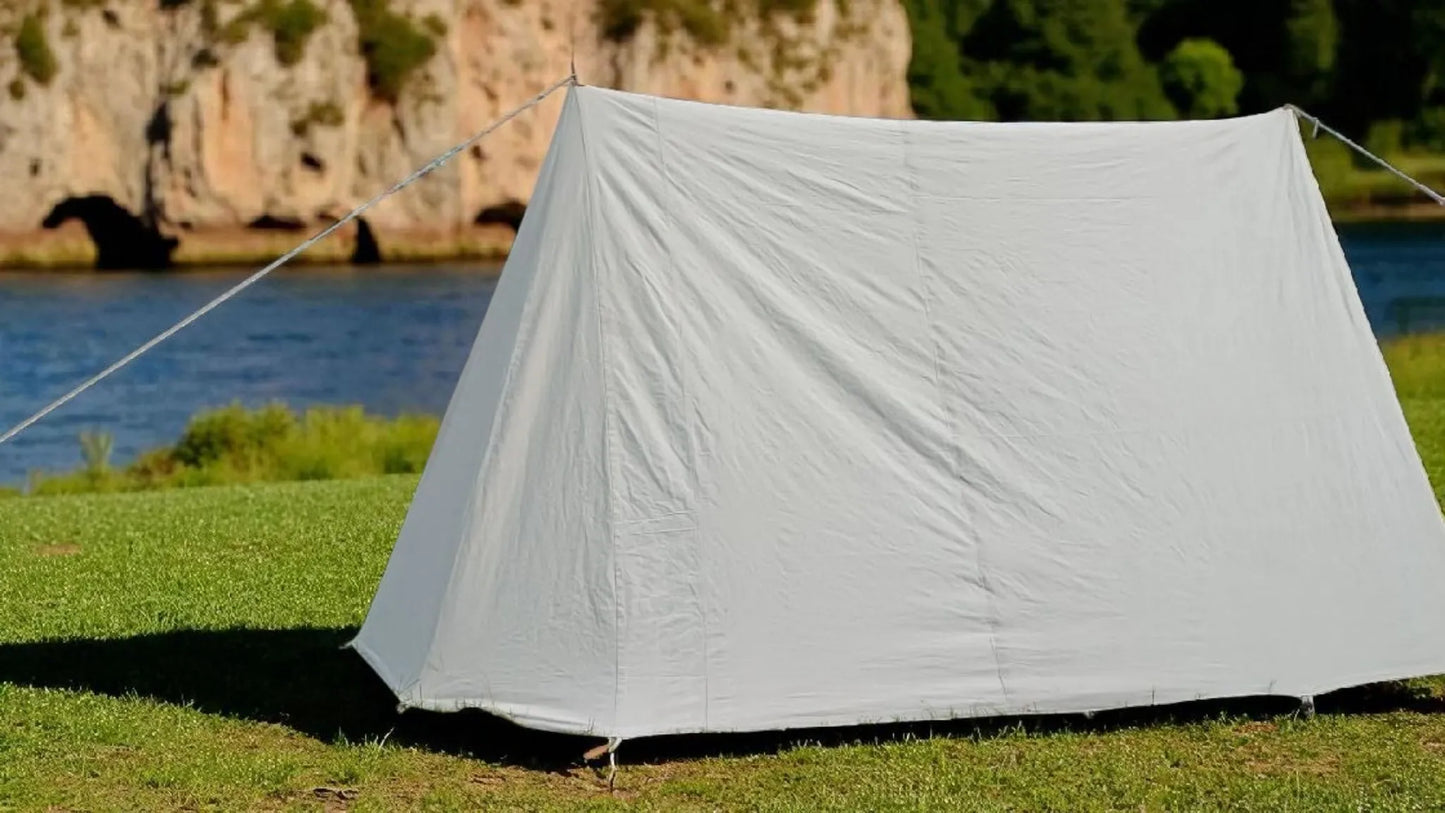 White tent set up on grass with a scenic background of water and cliffs.