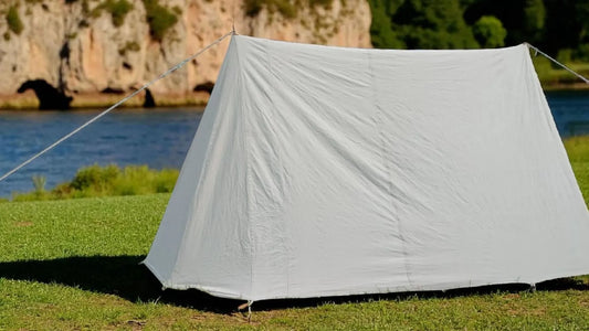 White tent set up on grass with a scenic background of water and cliffs.