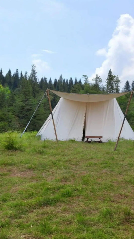 White tent with a tarp in a grassy field with trees in the background