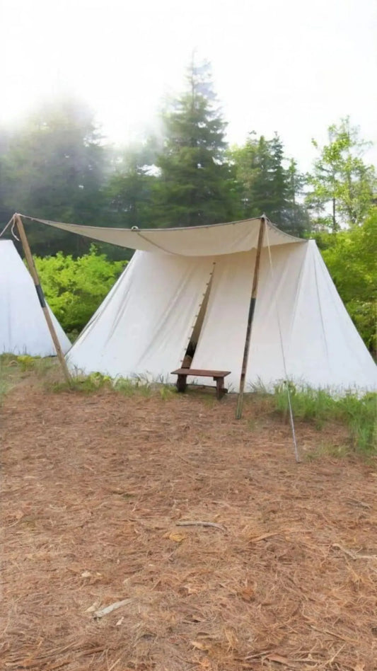 White canvas tent with a wooden bench in a forest setting