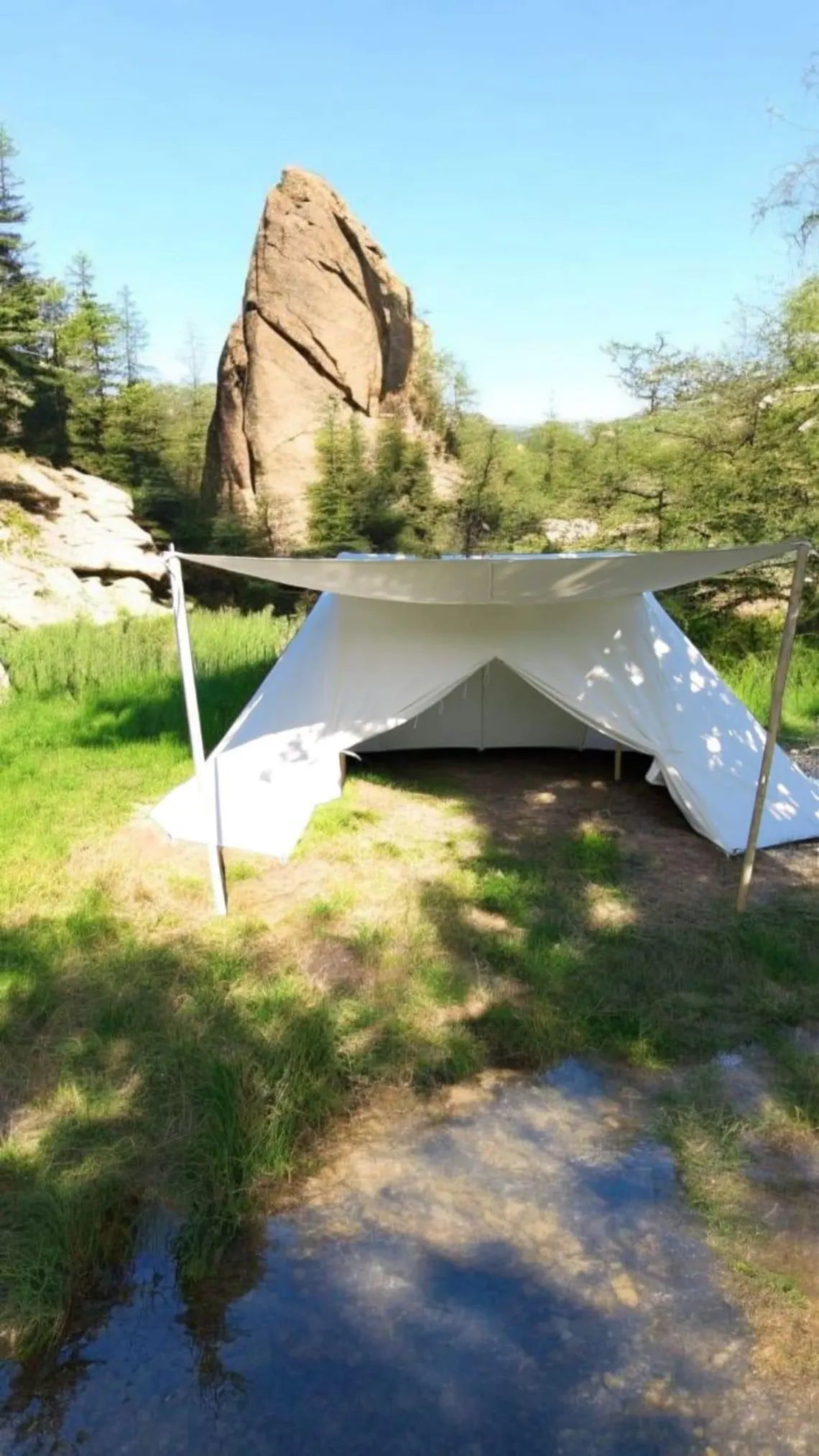 White tent set up in a natural outdoor setting with trees and rocks in the background