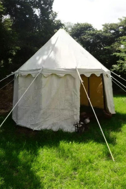 White bell tent with yellow interior on grassy area with trees in the background