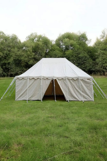 Large white tent set up on a grassy field with trees in the background