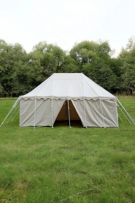 Large white tent set up on a grassy field with trees in the background