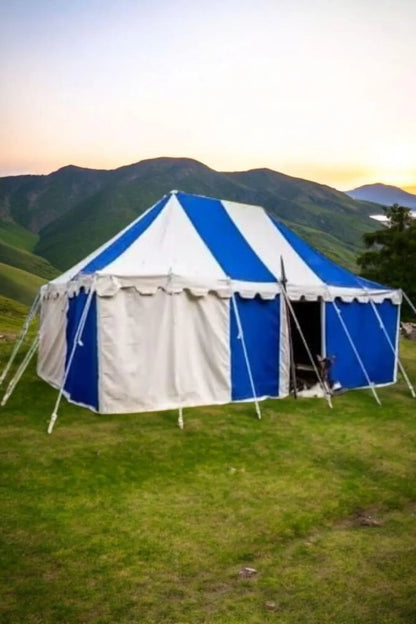 Blue and white tent set up in a grassy area with mountains in the background