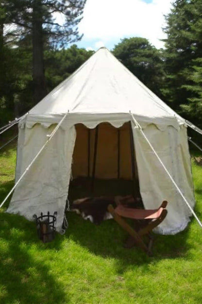 White bell tent with wooden furniture on a grassy area with trees in the background