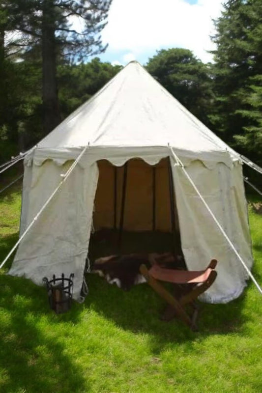 White bell tent with wooden furniture on a grassy area with trees in the background