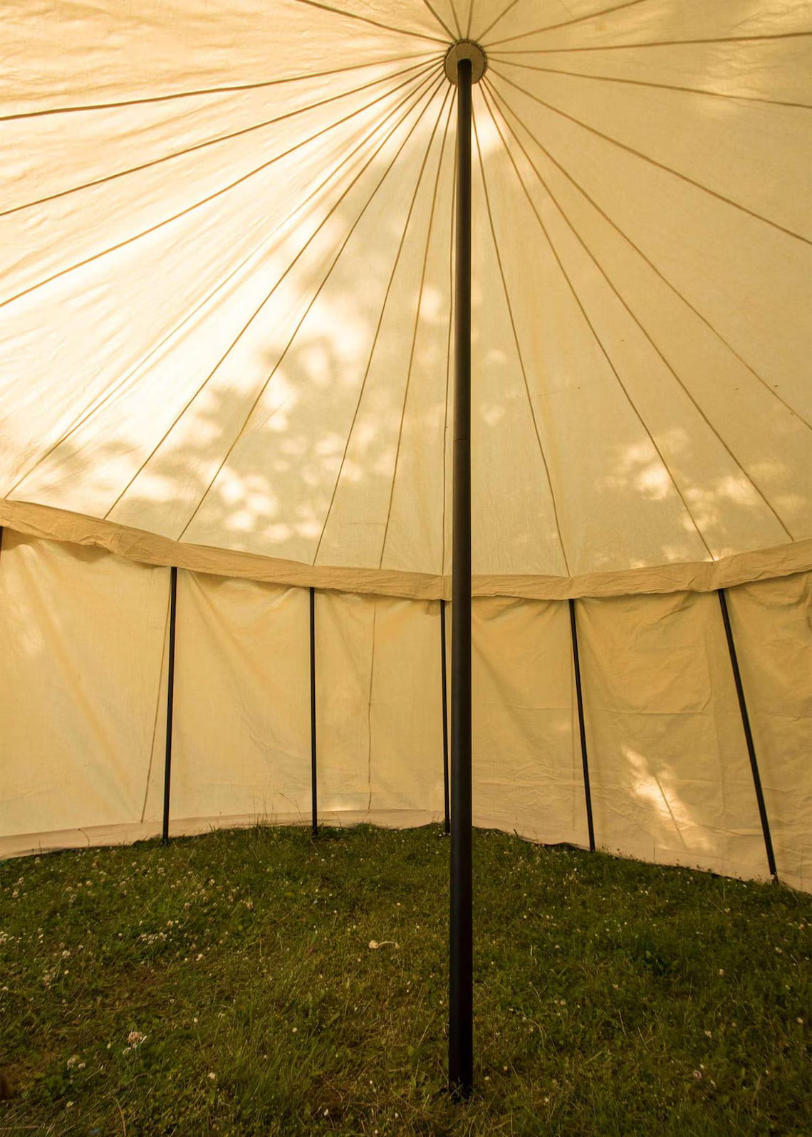 Close-up of a beige tent with a central pole on grass