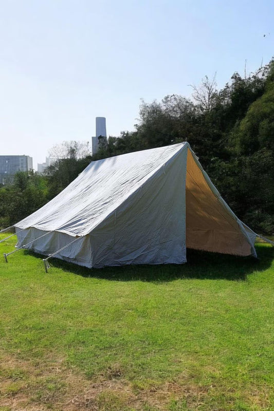 White tent on grass with trees and buildings in the background