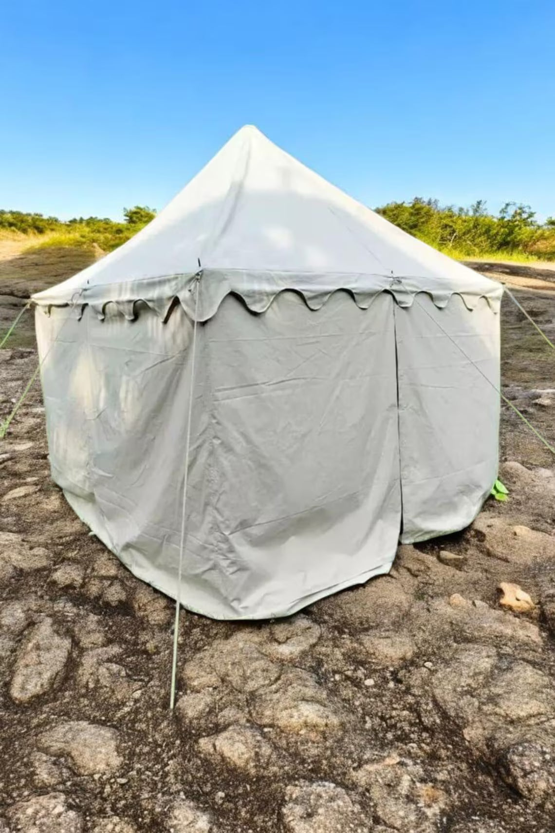 Gray tent set up on a rocky ground with a clear blue sky