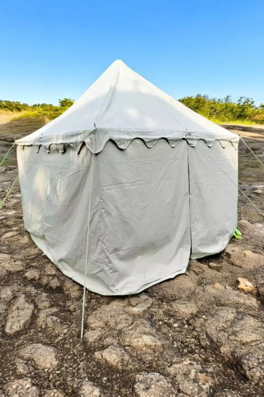 Gray tent set up on a rocky ground with a clear blue sky