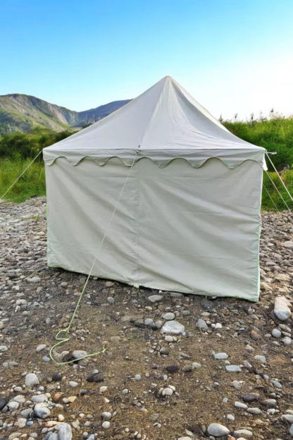 White tent set up on a rocky ground with mountains in the background
