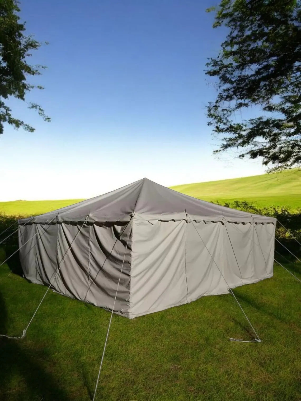 Large outdoor tent set up on grass with a clear blue sky
