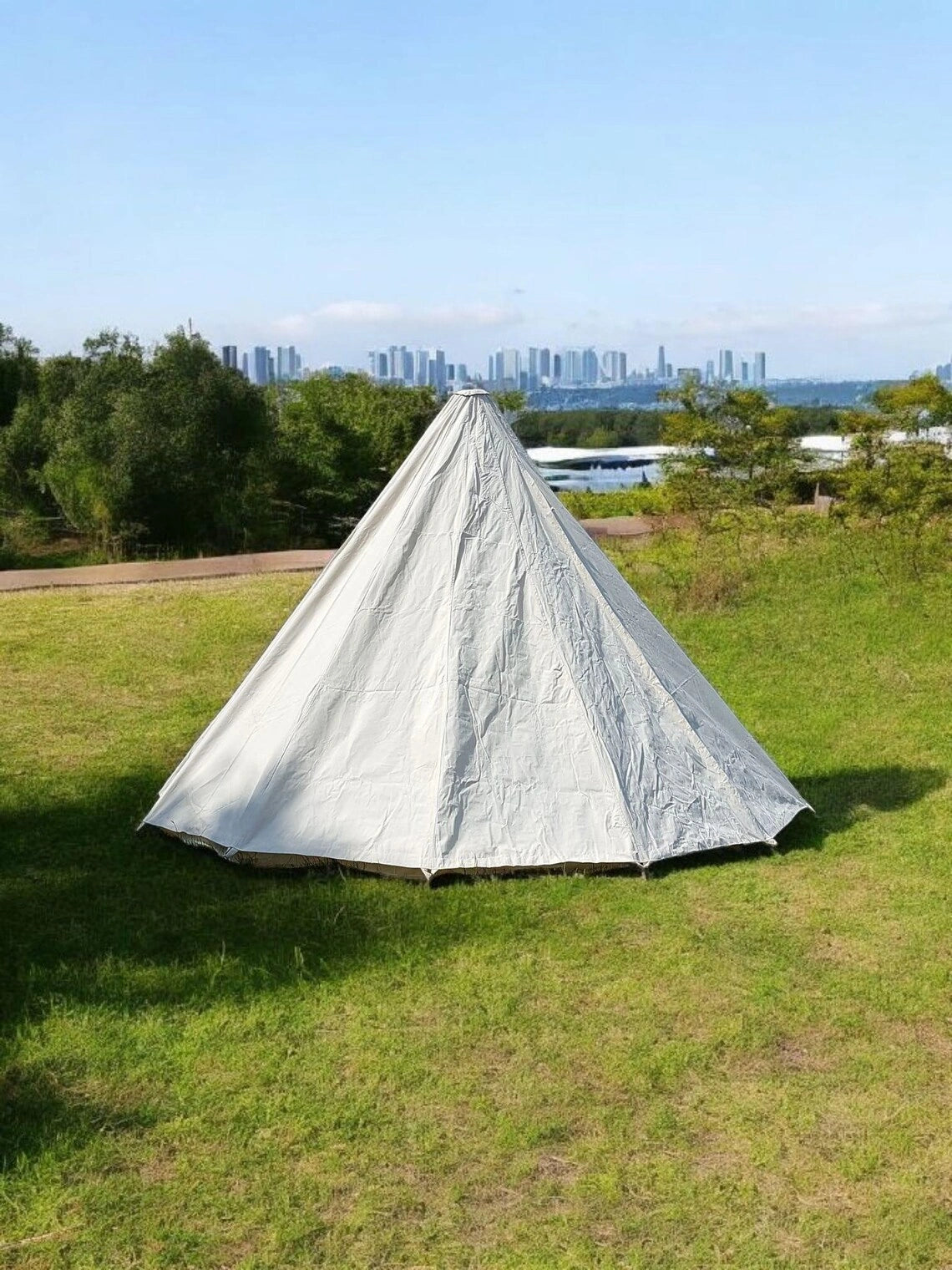 Camping tent on grass with city skyline in the background