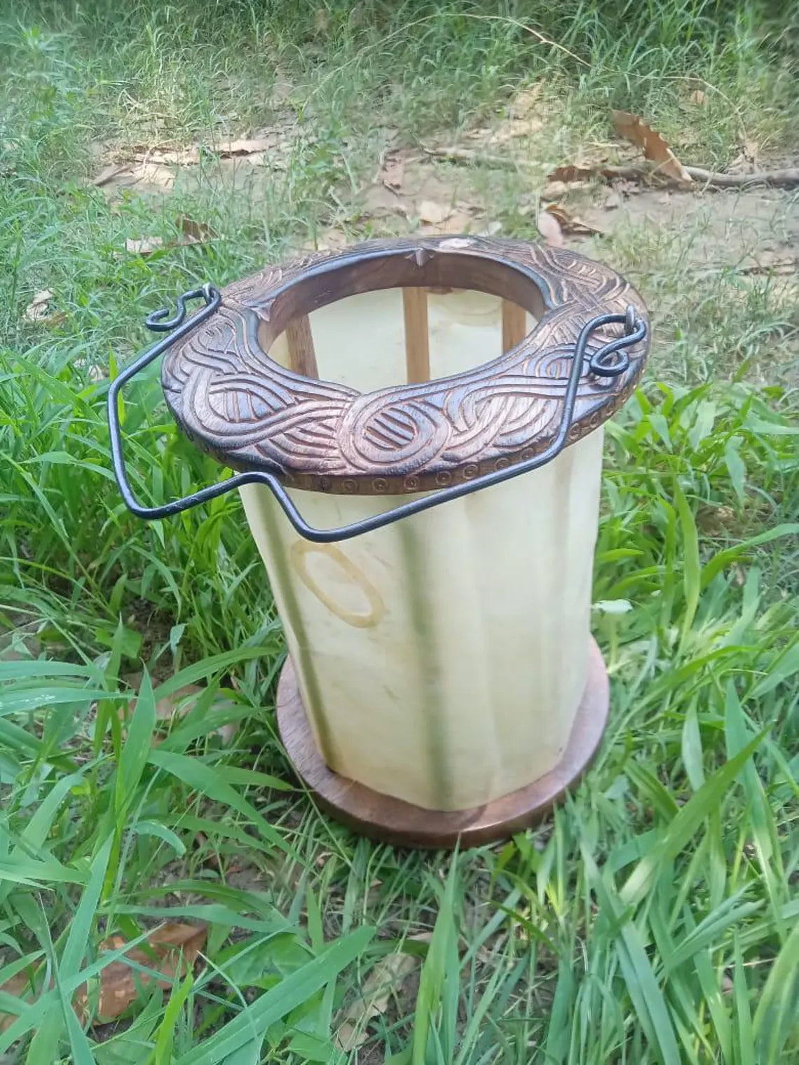 Decorative candle holder with intricate design on a grassy background