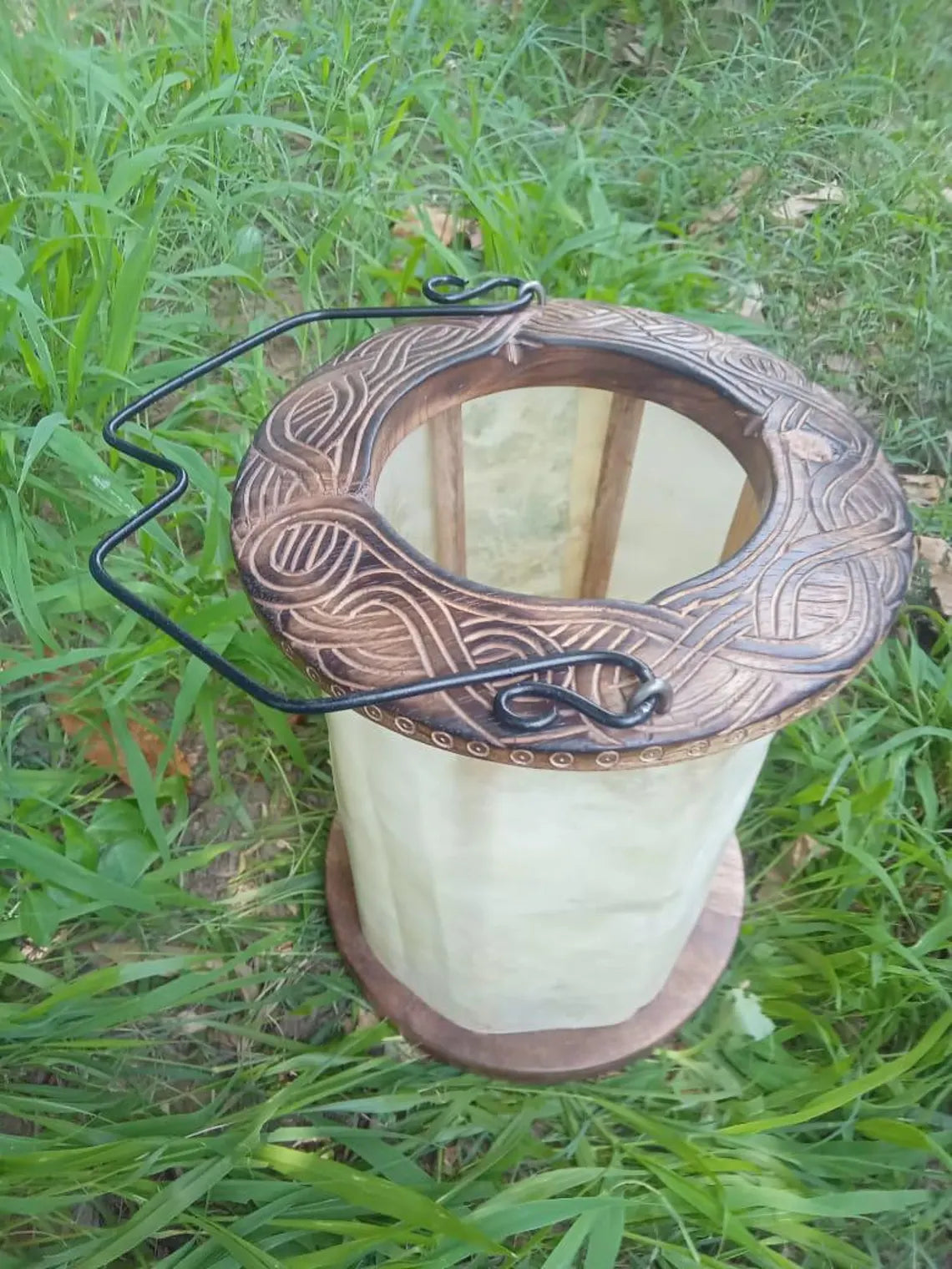 Decorative bird feeder with intricate design on a grassy background