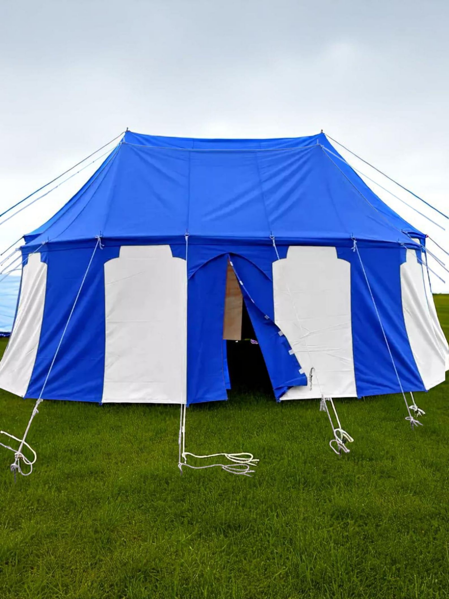 Blue and white tent set up on grass with a clear sky background