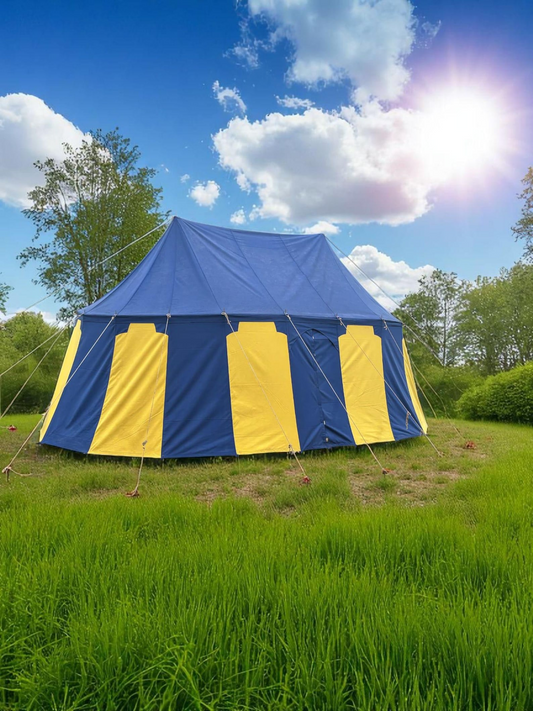 Blue and yellow striped tent in a grassy field with trees and blue sky.