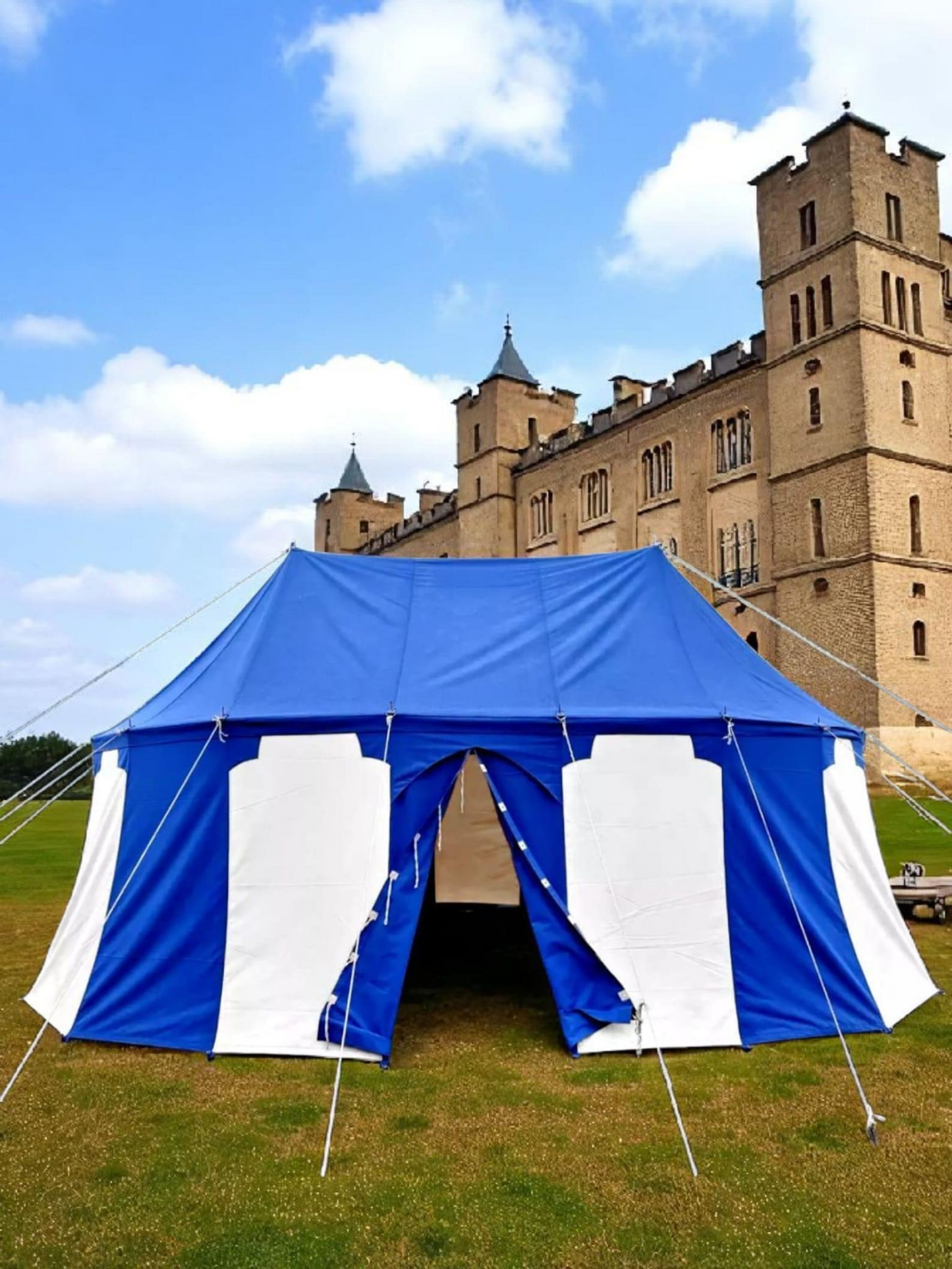 Blue and white tent set up outdoors with a castle in the background