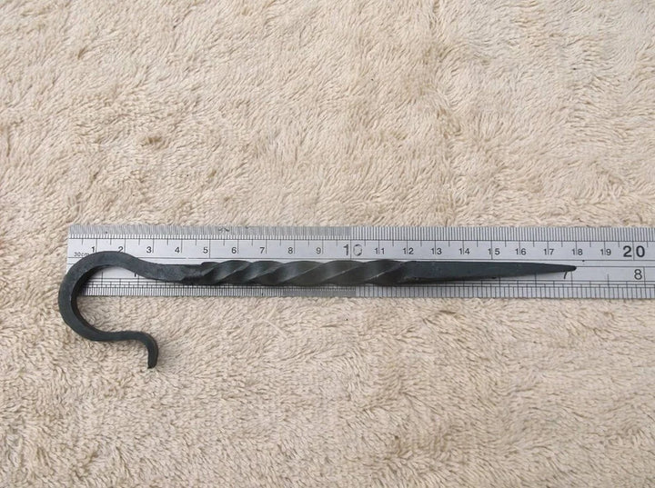 Metal hook with measuring tape on a textured beige surface