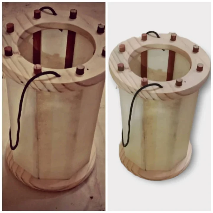 Wooden cylindrical device with metal rods and a black cable on a white background