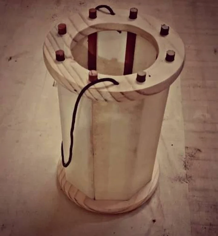 Wooden cylindrical device with electrical components on a concrete floor